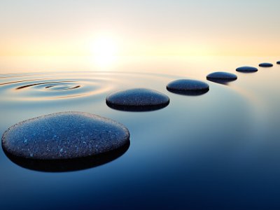 Dark stones in calm water with evening sun with horizon - tranquil scenery